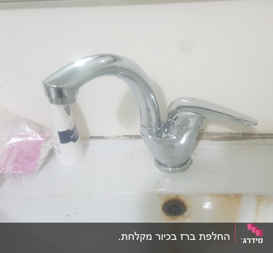 ברז כרום עם כתמי חלודה בכיור לבן